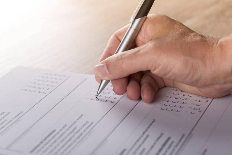 A hand with pen marks off ratings