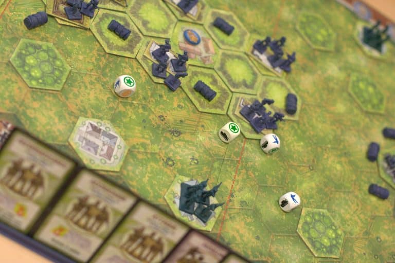A view of a boardgame with soldier, tank, and obstacle minis + dice